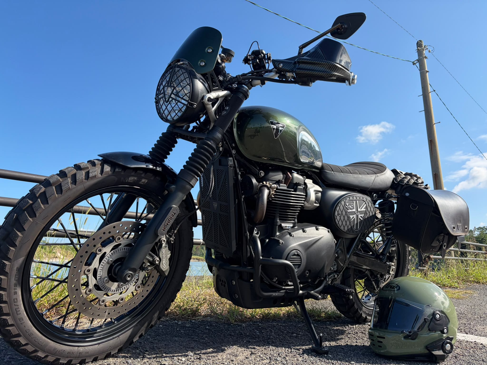Triumph Scrambler personnalisée avec caches latéraux LMC, photographiée en extérieur